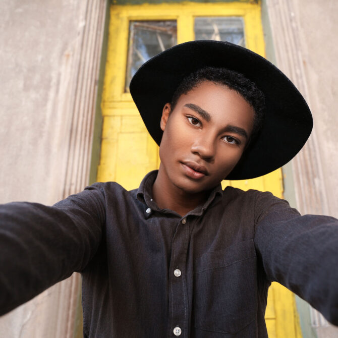 Stylish young African-American man taking selfie outdoors